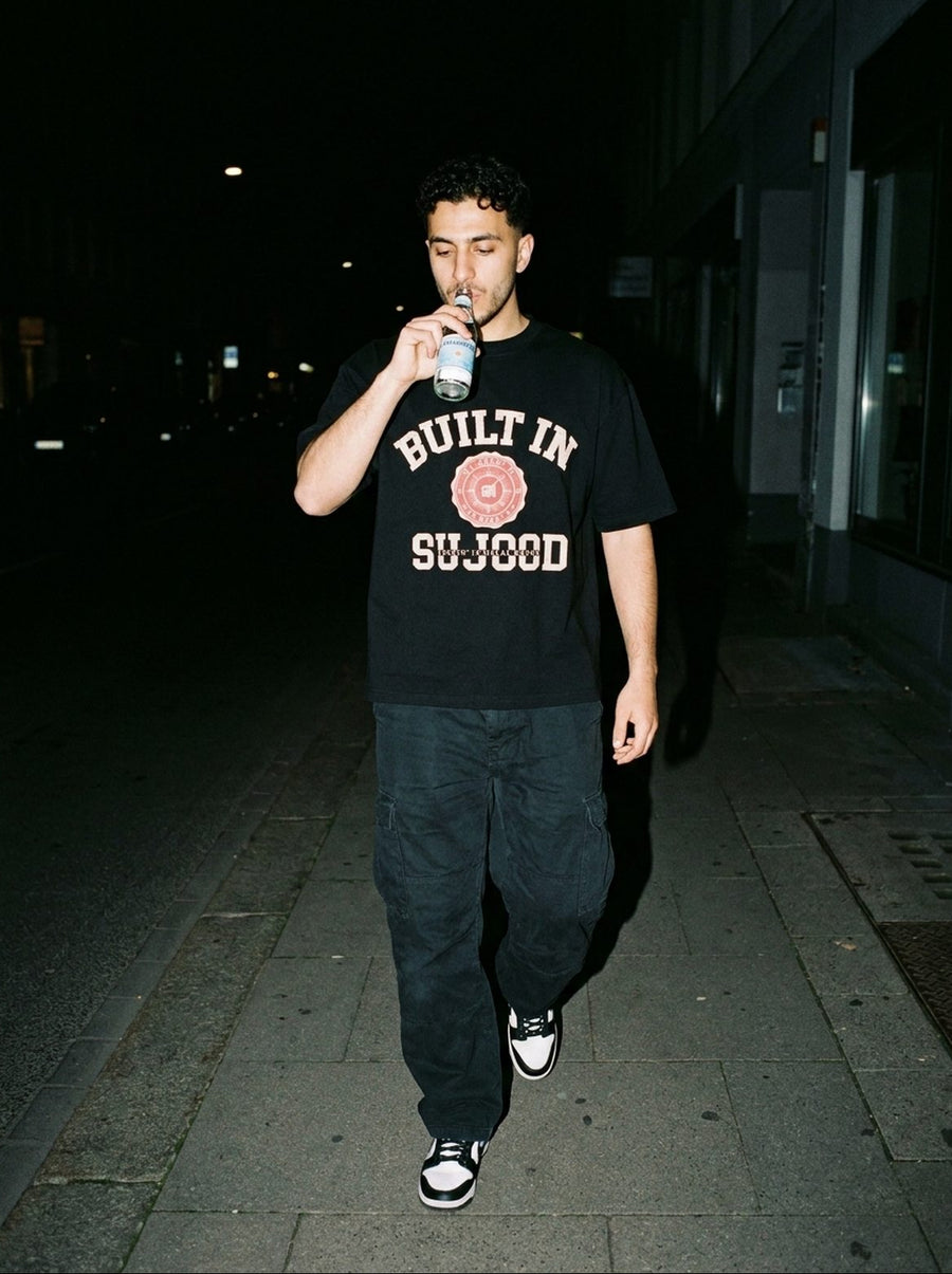 Built in Sujood black tee on a city street at night