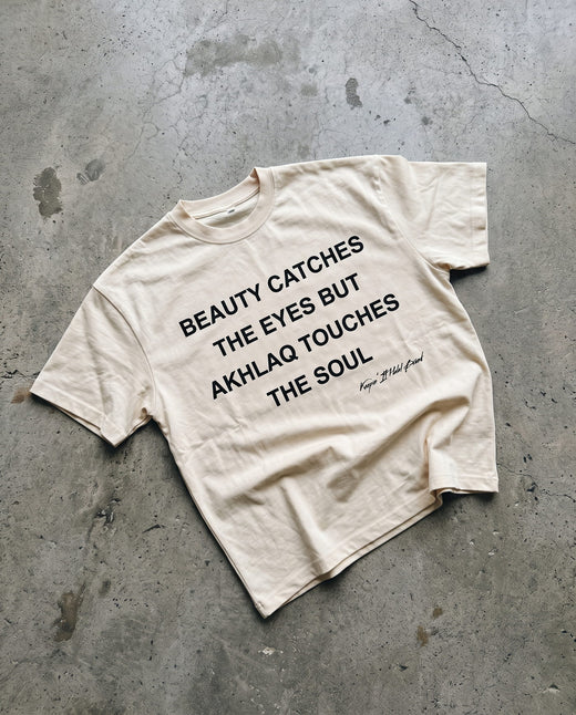 Akhlaq Over Beauty natural boxy tee laid flat on concrete