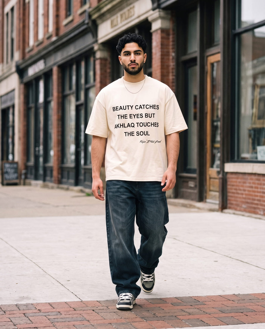 Akhlaq Over Beauty natural boxy tee walking a shopfront street