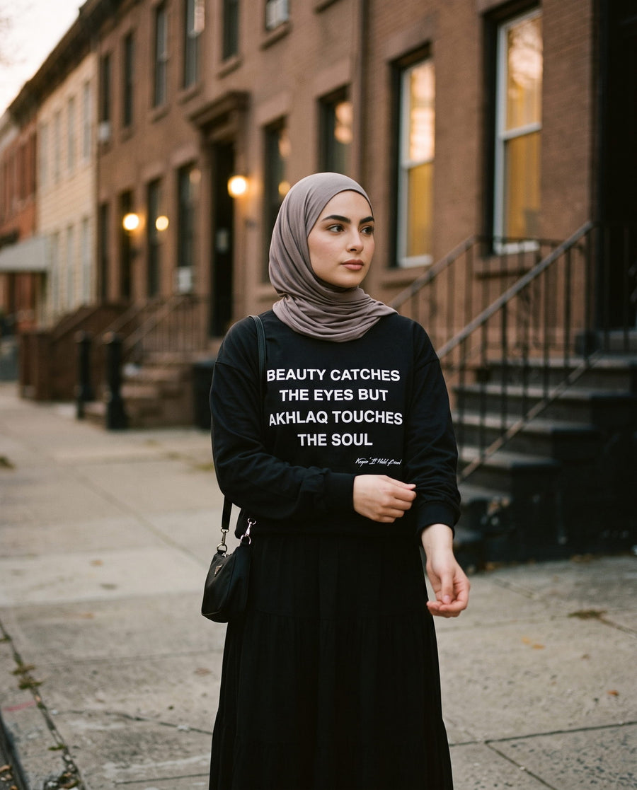 Akhlaq Over Beauty black long sleeve on a brownstone street at dusk