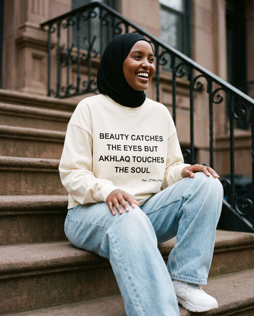 Akhlaq Over Beauty bone long sleeve seated on a stoop