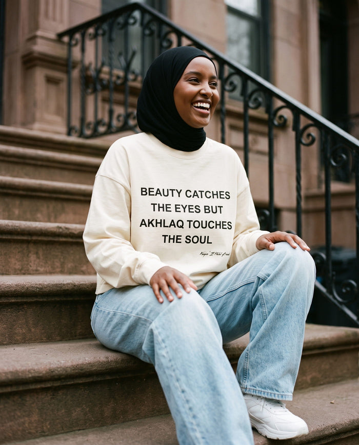 Akhlaq Over Beauty bone long sleeve seated on a stoop