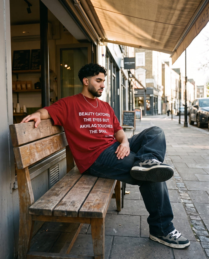 Akhlaq Over Beauty red heavy tee on a cafe bench