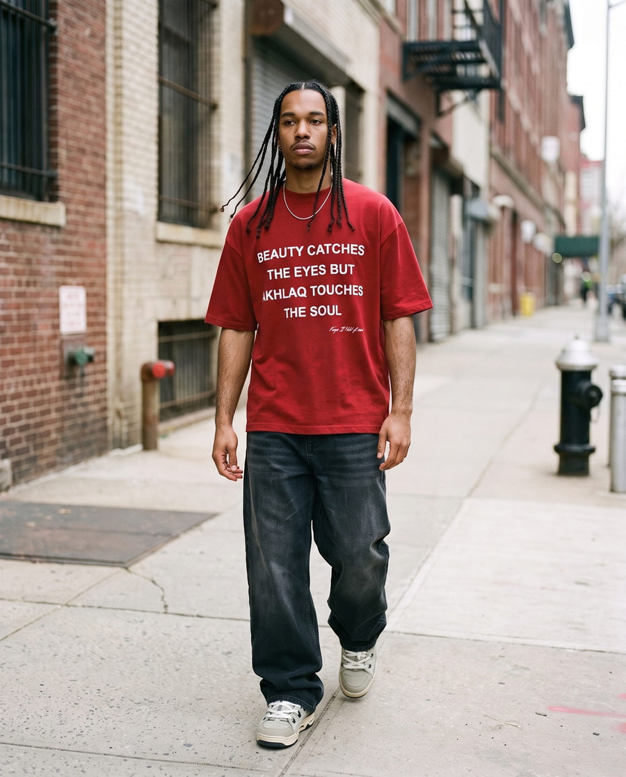 Akhlaq Over Beauty red heavy tee walking a brick pavement