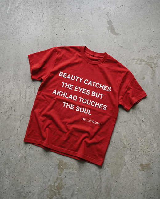 Akhlaq Over Beauty red heavy tee laid flat on concrete