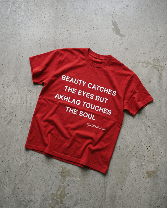 Akhlaq Over Beauty red heavy tee laid flat on concrete