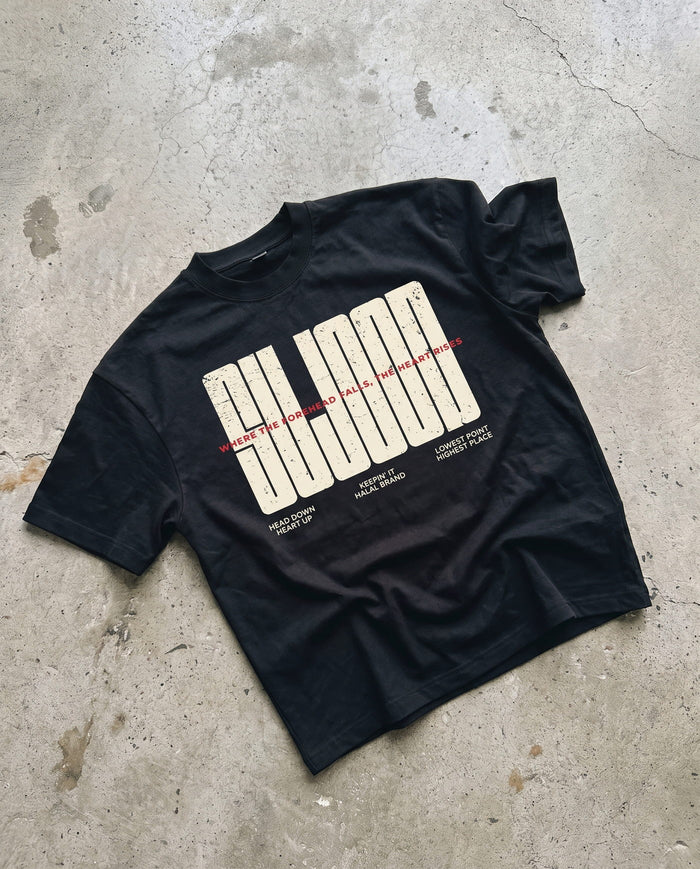 Sujood for the Heart black boxy tee laid flat on concrete