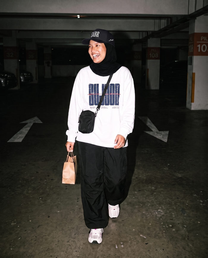 Sujood for the Heart white long sleeve in a parking garage