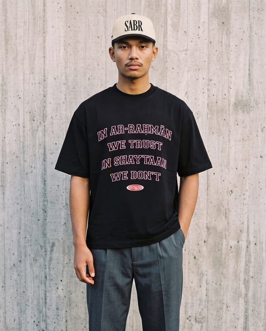 In Ar-Rahman We Trust black boxy tee against board-formed concrete