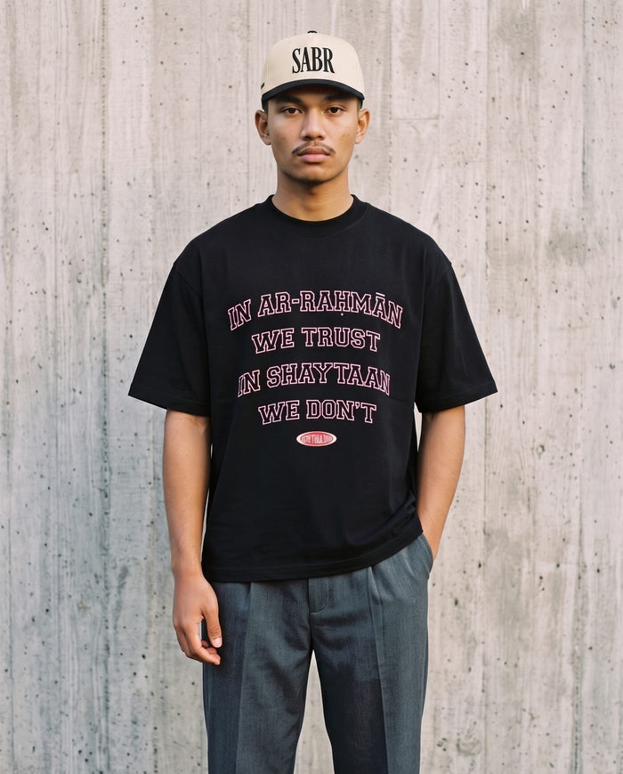 In Ar-Rahman We Trust black boxy tee against board-formed concrete