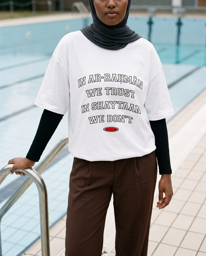 In Ar-Rahman We Trust white boxy tee on an empty pool deck