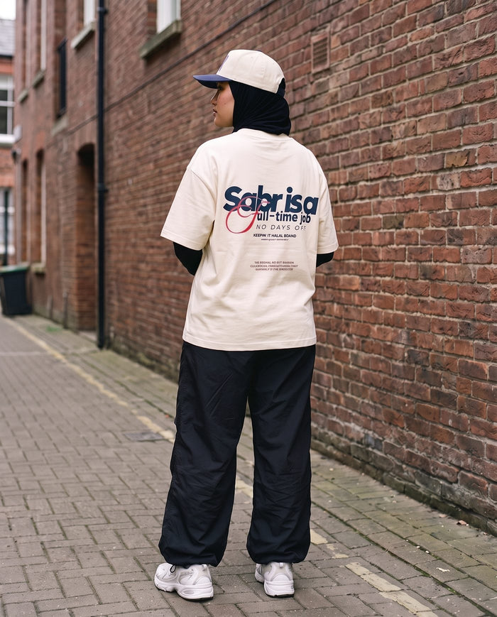Full-Time Sabr natural boxy tee back print against a brick wall