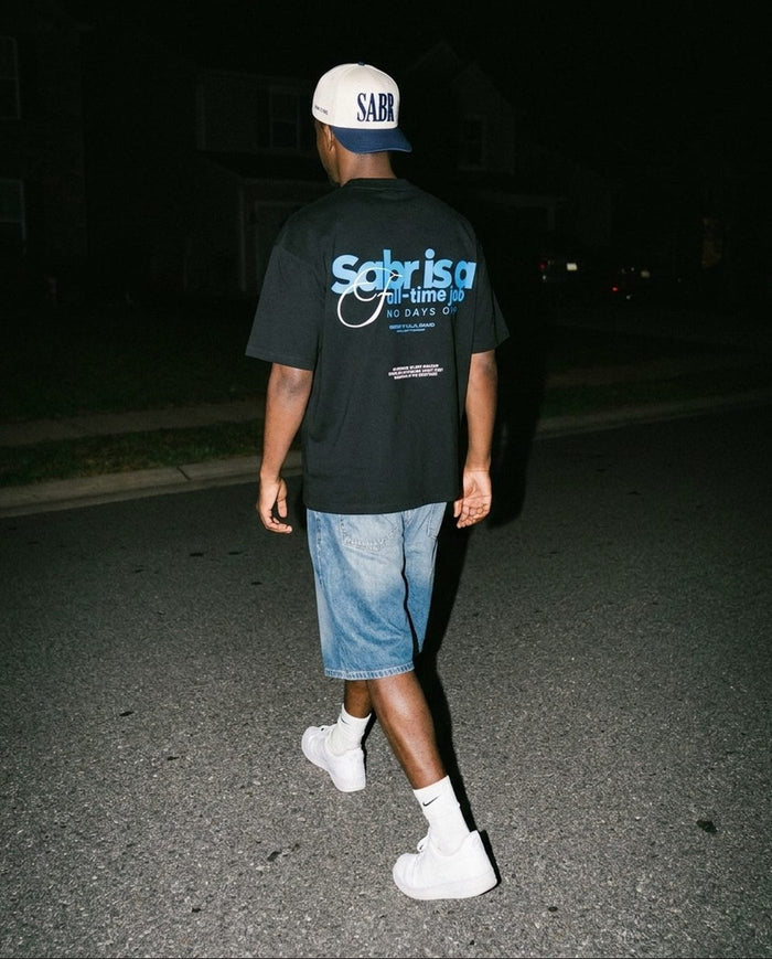 Sabr Cap in ivory with a navy brim worn with the black Full-Time Sabr tee on a night street