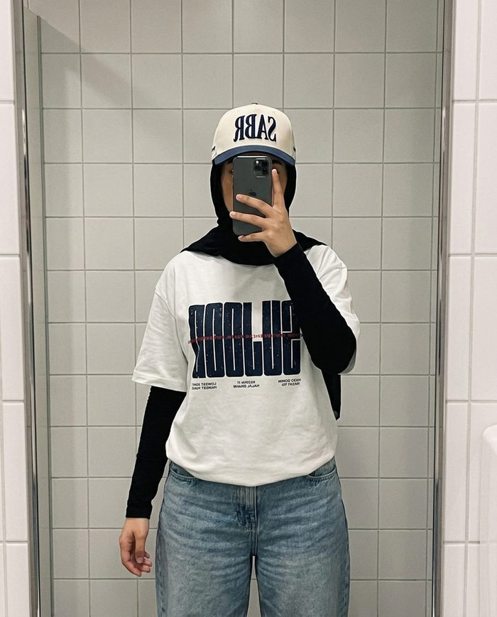 Sabr Cap in ivory with a navy brim worn with the white Sujood for the Heart tee in a tiled mirror selfie