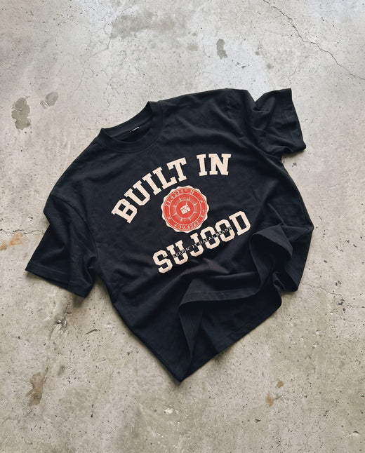 Built in Sujood black boxy tee laid flat on concrete