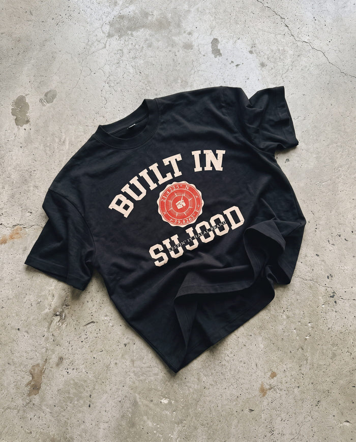 Built in Sujood black boxy tee laid flat on concrete