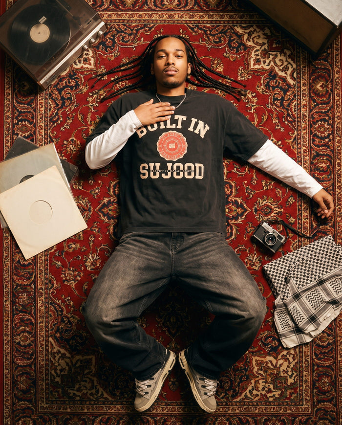 Built in Sujood black boxy tee shot from above on a Persian rug