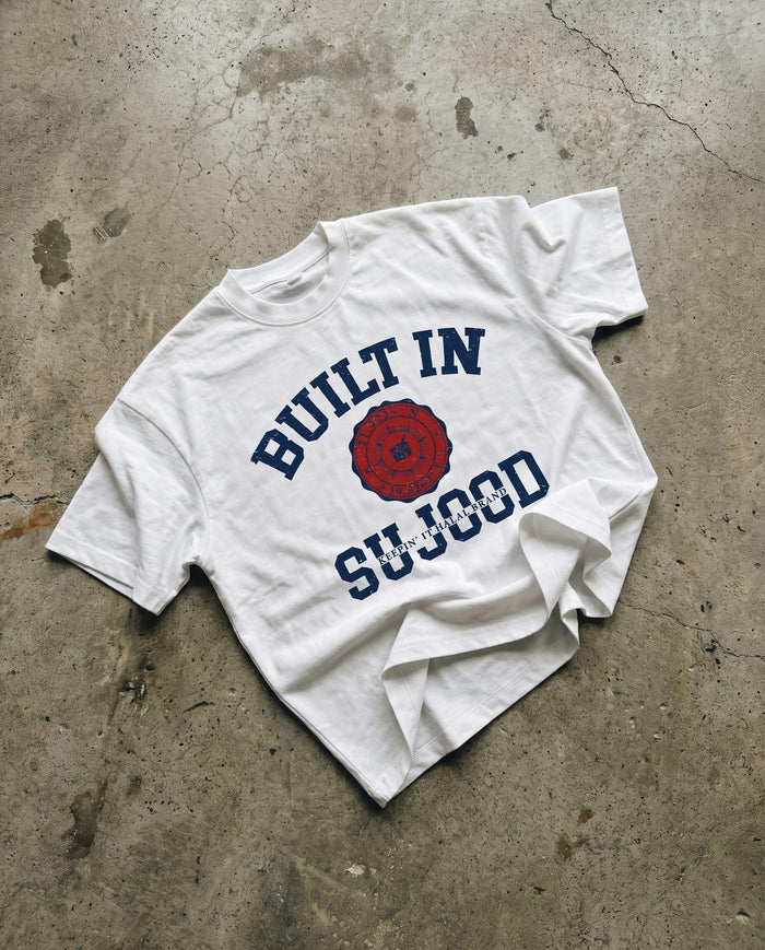 Built in Sujood white boxy tee laid flat on concrete