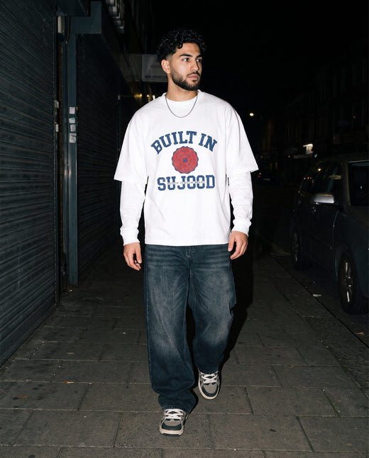 Built in Sujood white boxy tee walking a night sidewalk