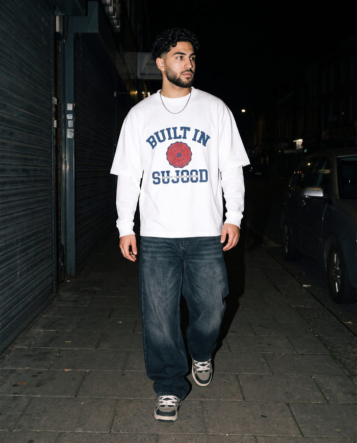 Built in Sujood white boxy tee walking a night sidewalk