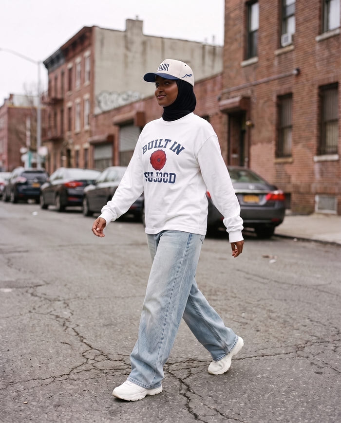 Built in Sujood white long sleeve, mid-stride on a city street