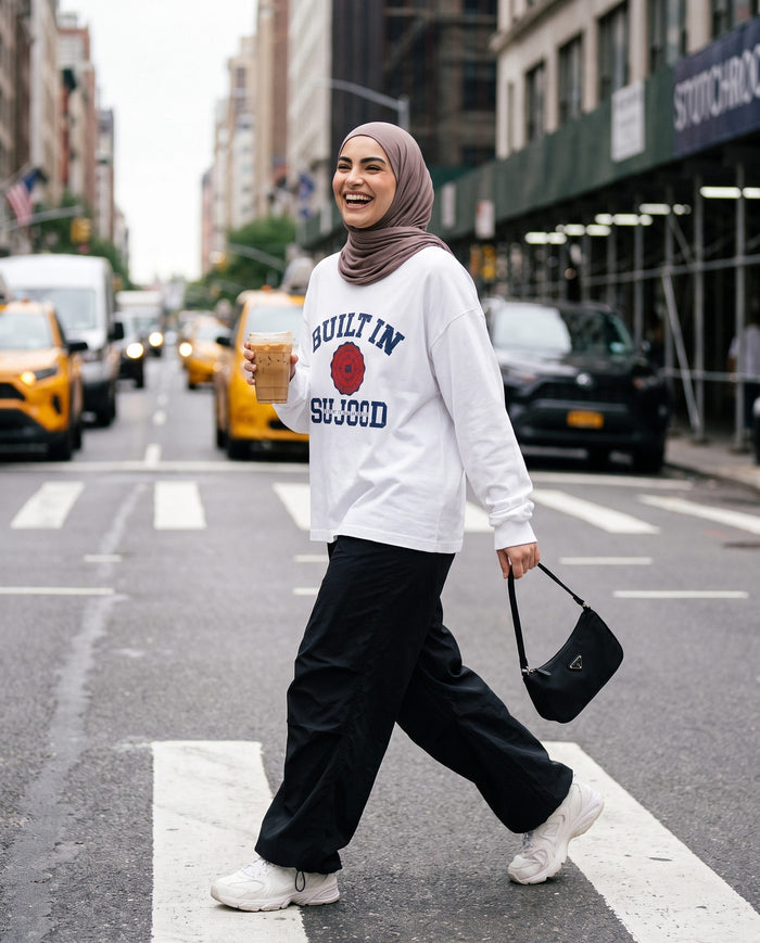 Built in Sujood white long sleeve crossing a busy city street